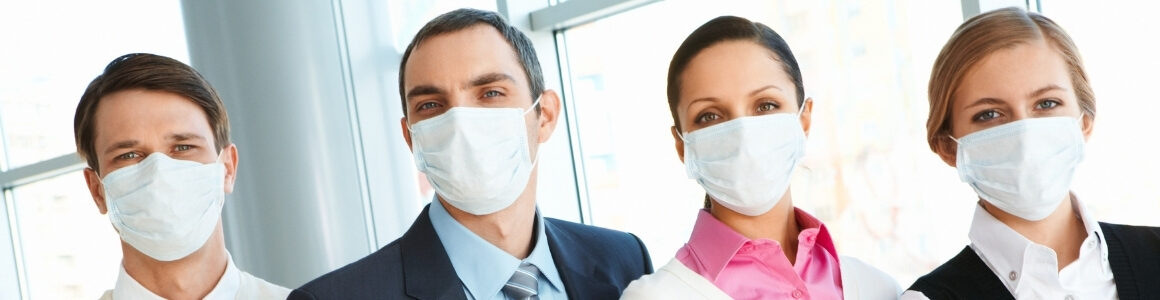 Two business men and two business women waring safety masks over nose and mouth.