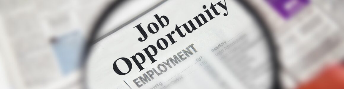 Zoomed in image through a magnifying glass focused on a newsletter headline "Job Opportunity".