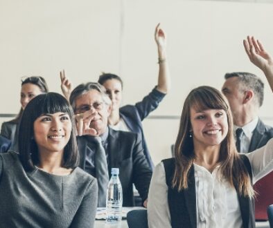 A group of people raising their hands in a leadership training class.