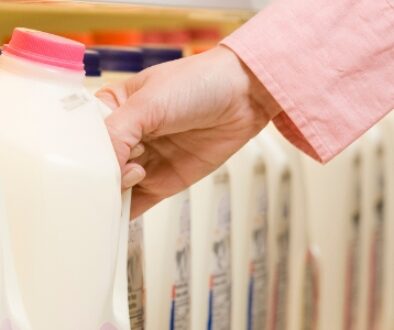 A customer selecting a gallon of milk in a grocery store.