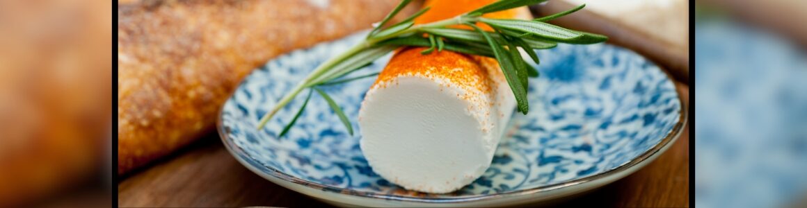 Chevre cheese log on a blue painted plate with a baguette on the side.