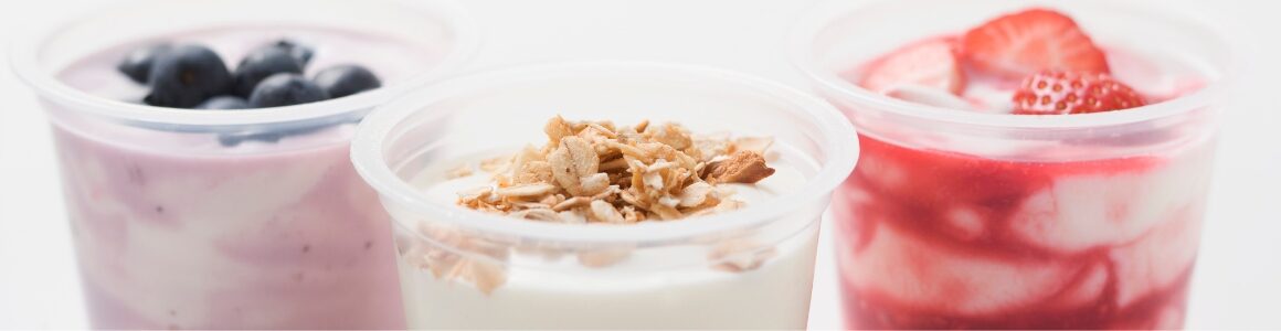 Yogurt in cups with various flavors including blueberries, strawberries, and granola.