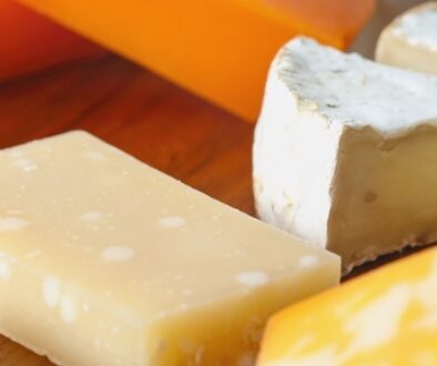 Assorted cheeses including brie, colby jack, parmesan, and cheddar on a wodden cutting board