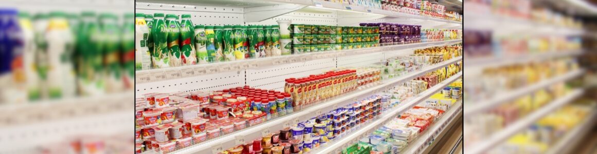 Refrigerated grocery store dairy case stocked with milk, yogurt, cheese and other packaged dairy products.