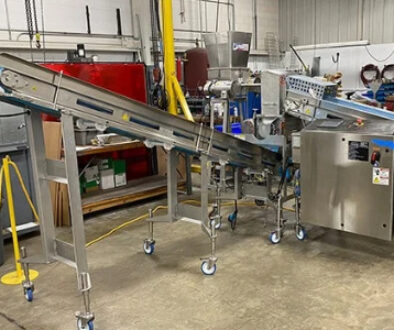 HART Design & Manufacturing cheese crumble line equipment with stainless steel conveyors in a manufacturing facility.